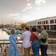 Friends walking over a waterfront bridge.