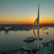 A modern tower next to the ocean at sunset
