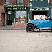 Two people inside a vintage car at a living museum