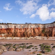 View of cliffs with white chalk overlaying red limestone in a colourful formation.